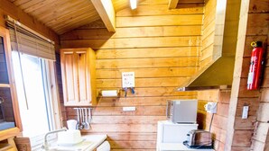 A compact kitchen with wooden walls, a washing machine, a microwave, and a toaster. - Steading Holidays - Strathconon (Acharacle)