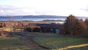 A rural landscape with a house, a path, and a body of water in the background. - Steading Holidays - Strathconon (Acharacle)
