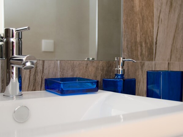 A modern bathroom with a white sink, chrome faucet, and blue soap dish.