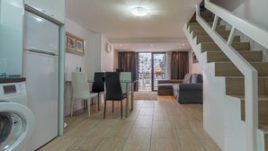Eine moderne Küche mit Waschmaschine, Essbereich mit Stühlen, einer Couch und einer Treppe.