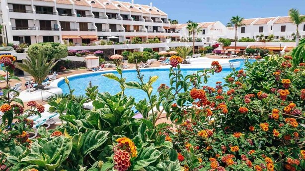 Ein Hotel mit Swimmingpool, umgeben von üppiger Vegetation und bunten Blumen.