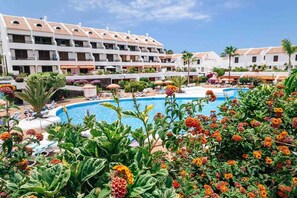 A hotel with a swimming pool surrounded by lush greenery and colorful flowers. - DUPLEX PARQUE SANTIAGO I (Playa de Las Americas)