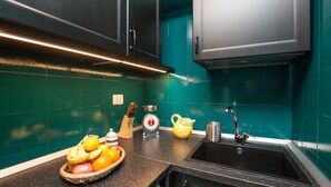 A kitchen with teal backsplash, black cabinets, a sink, and a fruit bowl. - My Rome View Suite Apartment (Rome)