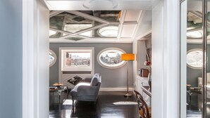 A room with a modern design, featuring a sofa, a table, and a lamp. There are two windows with views of the city. - My Rome View Suite Apartment (Rome)