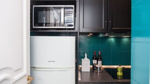A compact kitchen with a white refrigerator, a microwave, and a teal backsplash. - My Rome View Suite Apartment (Rome)