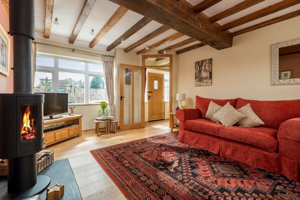 A cozy living room with a fireplace, a red sofa, and a patterned rug.