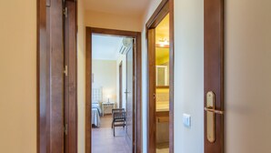 A hallway leading to a bedroom with a bed, bedside table, and a bench. - Prado Golf - Isla Canela Golf GPHG77P68 (Isla Canela)