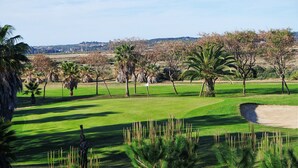 A golf course with well-maintained grass, palm trees, and a clear sky. - Prado Golf - Isla Canela Golf GPHG77P68 (Isla Canela)