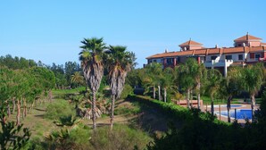 A large building with multiple roofs, surrounded by palm trees and a pool area. - Prado Golf - Isla Canela Golf GPHG77P68 (Isla Canela)