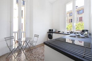 Une cuisine compacte équipée d’un évier, d’un four à micro-ondes et d’un petit coin repas avec une chaise et une table.