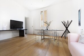 A modern living room with a flat-screen TV, a glass dining table, and a pink sofa. - UR-NEST Battisti 2 Deluxe (Bologna)