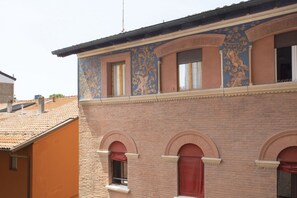 Un edificio con fachada de ladrillo, ventanas arqueadas y pinturas decorativas en la pared.