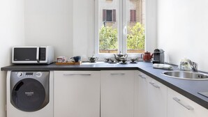 A compact kitchen with a washing machine, a microwave, and a sink. - UR-NEST Battisti 2 Deluxe (Bologna)