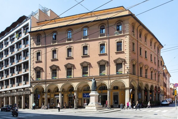 Ein historisches Gebäude mit mehreren Stockwerken, Bogenfenstern und einer Statue in der Mitte.
