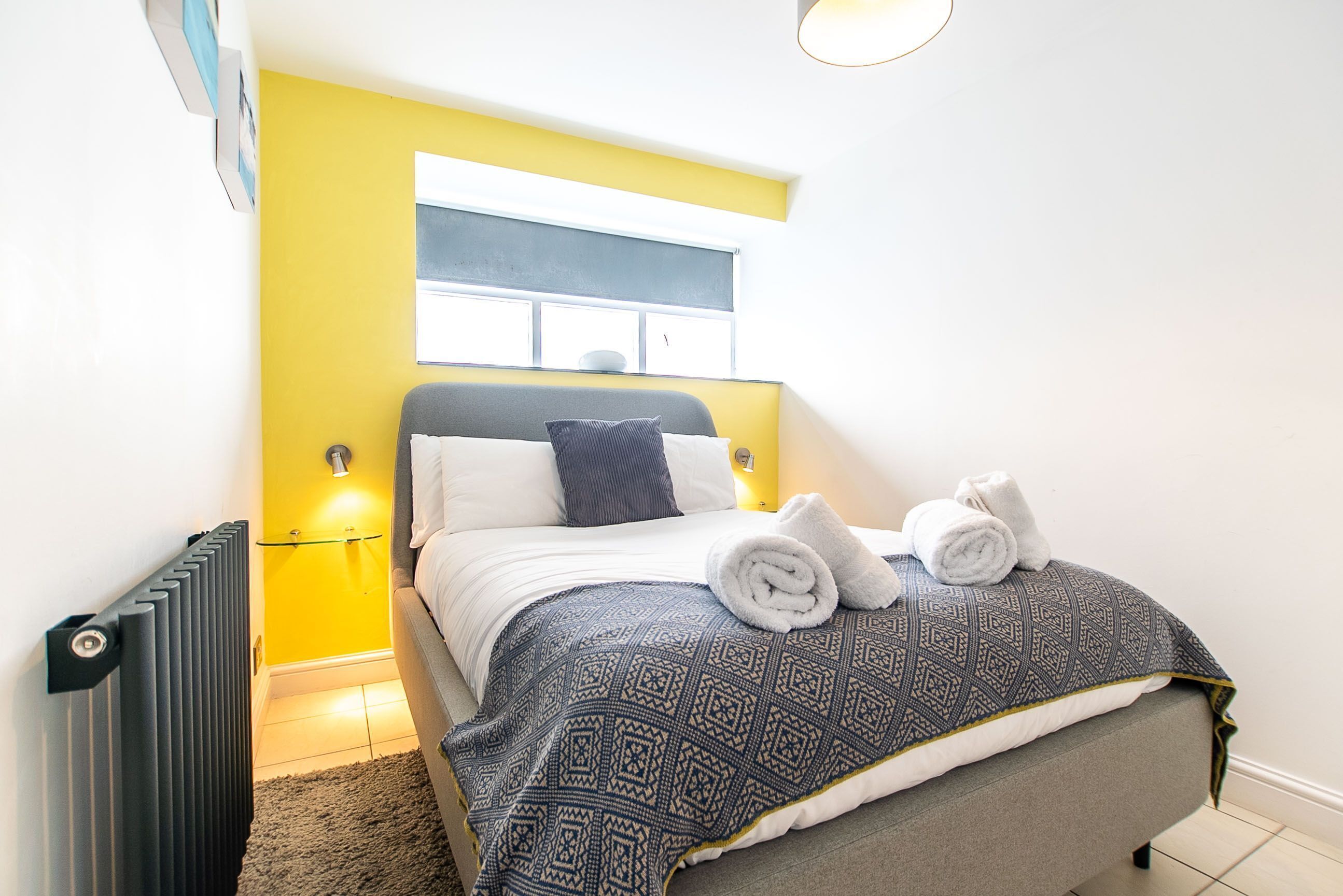 Ein modernes Schlafzimmer mit einem Bett, einem Heizkörper und einem Fenster.