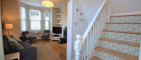 A living room with a sofa, TV, and a staircase with patterned steps.