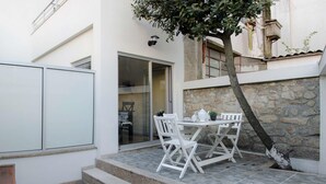 A patio with a table and chairs, a stone wall, and a tree. - Porto Histórico 4 - Superior one bedroom apartment (Porto)