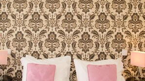 A hotel room with a patterned wallpaper, two white pillows with pink accents, and bedside lamps. - Porto Histórico 4 - Superior one bedroom apartment (Porto)