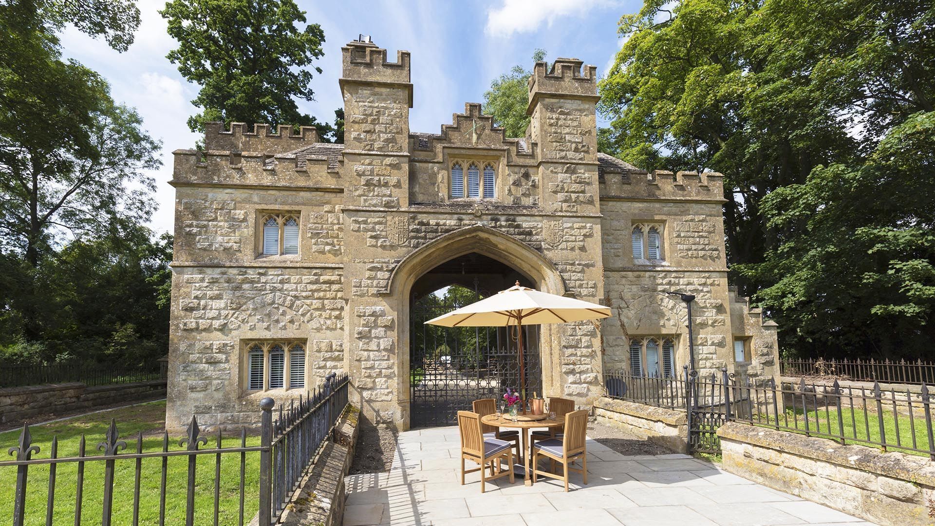 A stone castle entrance with a gated patio area featuring a table and chairs.
