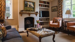 A cozy living room with a fireplace, a television, a bookshelf, and comfortable seating. - A sudeley castle cottage that sleeps 6 guests  in 3 bedrooms (Cheltenham)