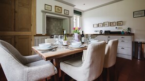 A dining area with a wooden table set for four, surrounded by upholstered chairs. - A sudeley castle cottage that sleeps 6 guests  in 3 bedrooms (Cheltenham)