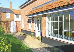 Traditional home with a brick facade, paved pathway, and a large window.