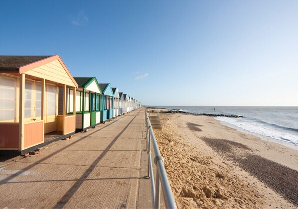 Beach huts line the seaside promenade, offering shelter and a safe path to the ocean.