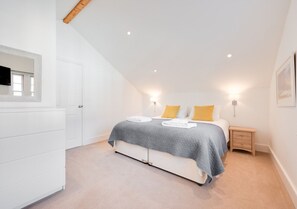 Relax in a serene bedroom with a large bed, bedside table, and dresser.