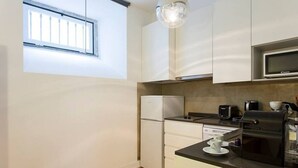 Een kleine keuken met witte kastjes, een ingebouwde magnetron, een koffiezetapparaat en een broodrooster.