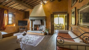 A cozy living room with a fireplace, a sofa, a TV, and a dining area. - Villa in Montevarchi with 5 bedrooms sleeps 12 (Montevarchi)