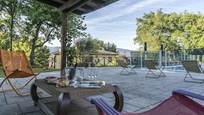 An outdoor patio with a table set for dining, surrounded by lounge chairs and a pool area. - Villa in Montevarchi with 5 bedrooms sleeps 12 (Montevarchi)
