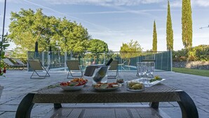 An outdoor dining area with a table set for a meal, surrounded by chairs and a pool in the background. - Villa in Montevarchi with 5 bedrooms sleeps 12 (Montevarchi)