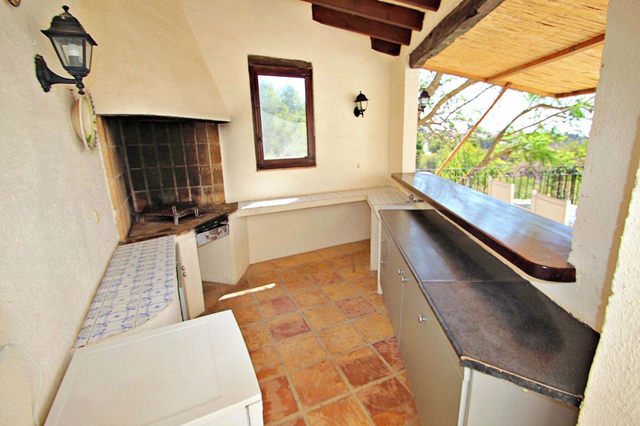 A compact kitchen with a tiled floor, a built-in oven, and a window overlooking greenery.