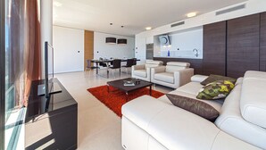 A modern living room with a sofa, a coffee table, and a dining area with chairs and a table. - Luxury Apartment the Ocean Dream I (Primošten)
