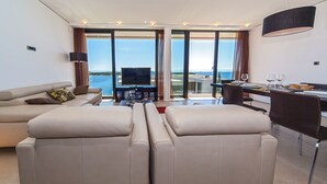 A modern living room with a sofa, a flat-screen TV, and a dining area with a table and chairs. - Luxury Apartment the Ocean Dream I (Primošten)