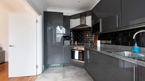 Een moderne keuken met donkere kastjes, een roestvrijstalen spoelbak en een ingebouwde oven.