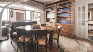 Ein Essbereich mit einem runden Tisch, Stühlen und einem Holzregal voller Bücher.
