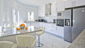 Une cuisine moderne avec des armoires blanches, des appareils en acier inoxydable et un comptoir en granit.