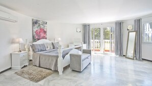 Une chambre spacieuse avec un grand lit, des tables de chevet, un miroir et une vue sur l’extérieur grâce à une porte-fenêtre coulissante.