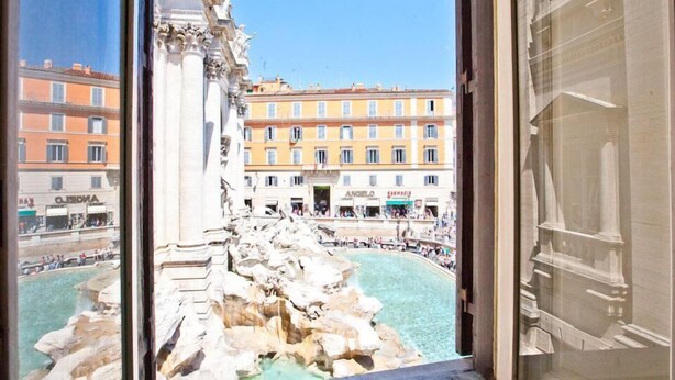 A view of the Trevi Fountain from inside a building, with the Spanish Steps and surrounding buildings in the background.