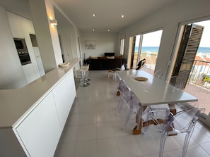 Enjoy ocean views from the spacious balcony, featuring a dining area with a large table and comfortable seating.