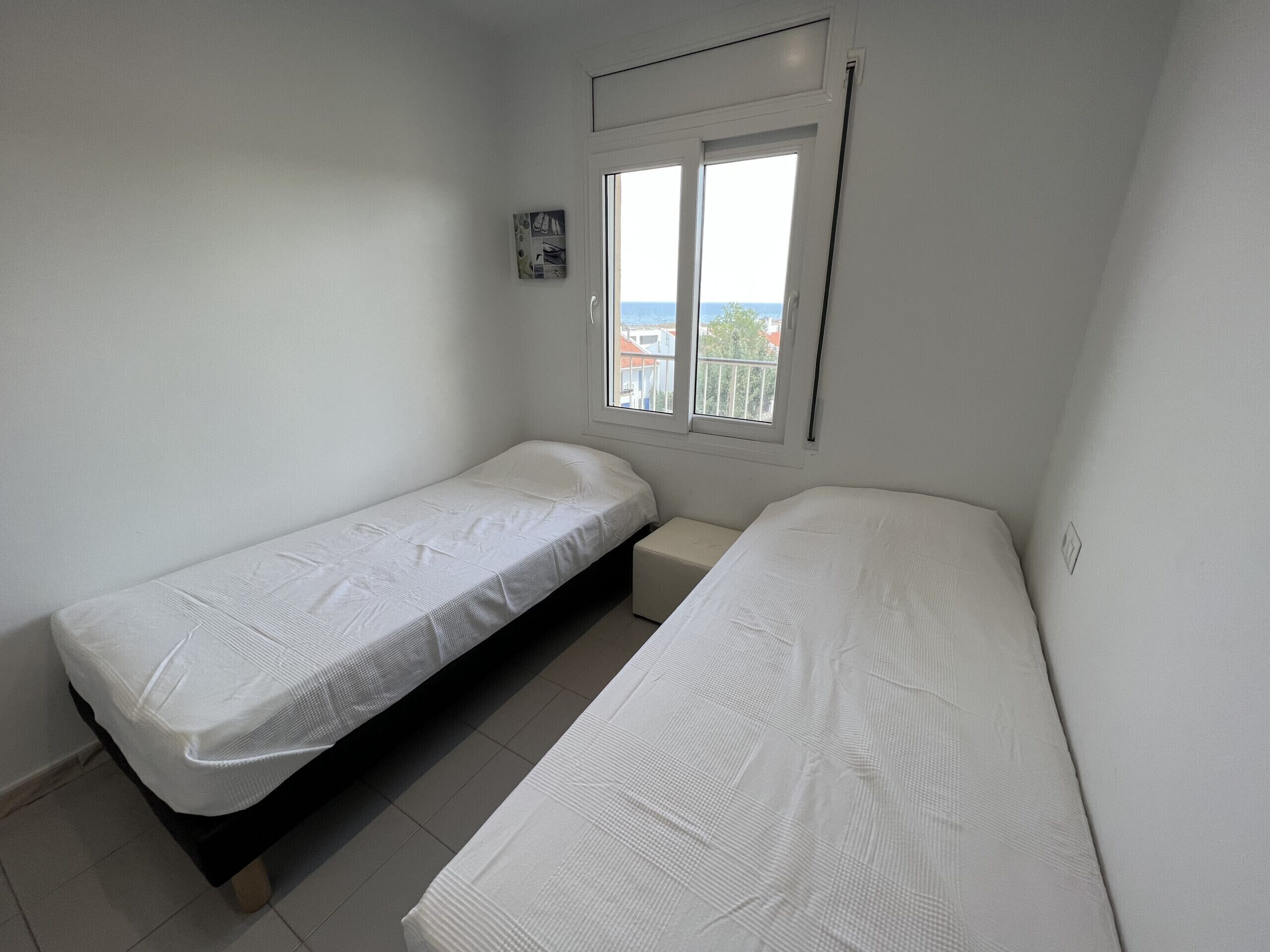 Et lille, rent værelse med to senge og et vindue med udsigt.