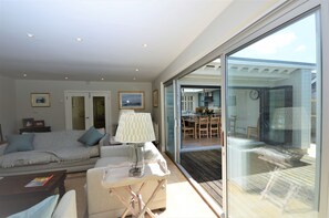 Un salon moderne avec un canapé, une table basse et une lampe. Une porte vitrée donne accès à un balcon doté d’une terrasse en bois.