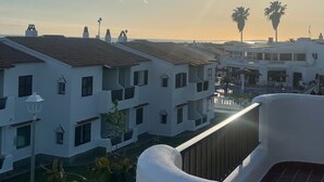 A residential area with white buildings, a balcony, and a clear sky with the sun setting. - 2 Bedroom Apartment , Son Bou (Son Bou)