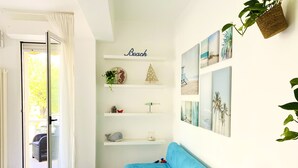 Une pièce lumineuse avec un canapé bleu, une console blanche et une étagère murale agrémentée d'objets décoratifs.