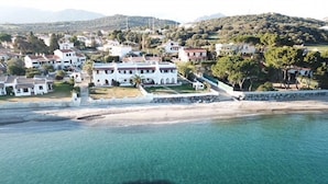 An aerial view of a coastal town with white buildings, a clear blue sea, and a hilly landscape in the background. - Beach house with private beach access  (Perd'e Sali)