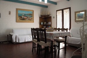 A dining area with a wooden table, chairs, and a painting on the wall.