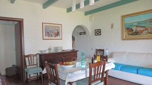 A dining area with a table set for two, a sofa, and a painting on the wall. - Beach house with private beach access  (Perd'e Sali)