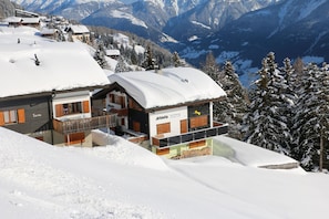 A snow-covered mountain lodge with a wooden exterior and a balcony. - Haus-Aristella (Riederalp)