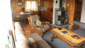 Una sala de estar acogedora con sofá, sillón y mesa de centro. Hay un comedor con mesa y sillas, y una cocina con estufa y refrigerador.